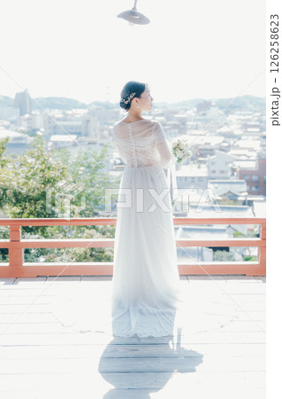高台の神社から町並みを望むウェディングドレス姿の女性のポートレート 126258623