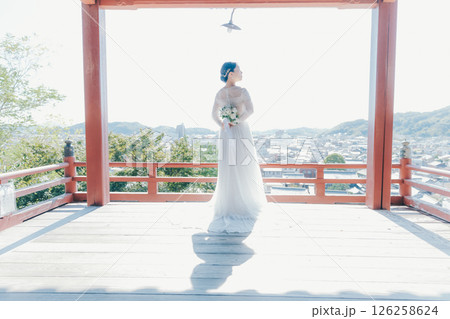 高台の神社から町並みを望むウェディングドレス姿の女性のポートレート 126258624