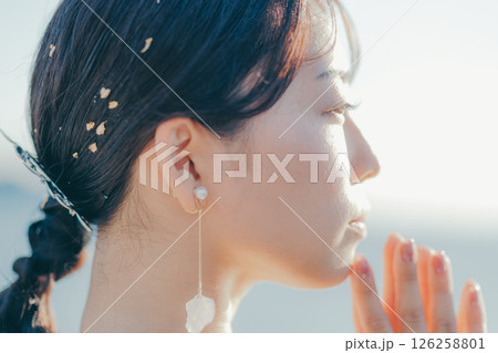 海辺の逆光に浮かぶウェディングドレス姿の女性のポートレート 126258801