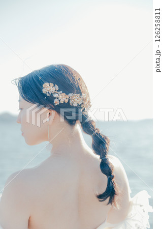 海辺の逆光に浮かぶウェディングドレス姿の女性のポートレート 126258811