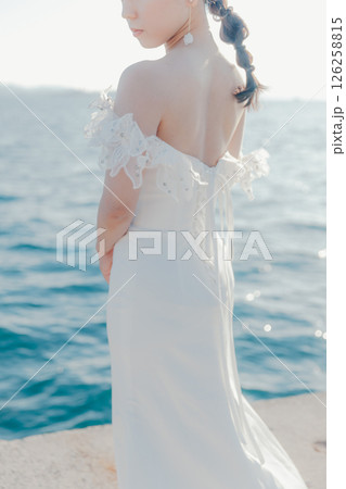 海辺の逆光に浮かぶウェディングドレス姿の女性のポートレート 海辺の逆光に浮かぶウェディングドレス姿の女性のポートレート 126258815