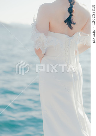 海辺の逆光に浮かぶウェディングドレス姿の女性のポートレート 海辺の逆光に浮かぶウェディングドレス姿の女性のポートレート 126258819
