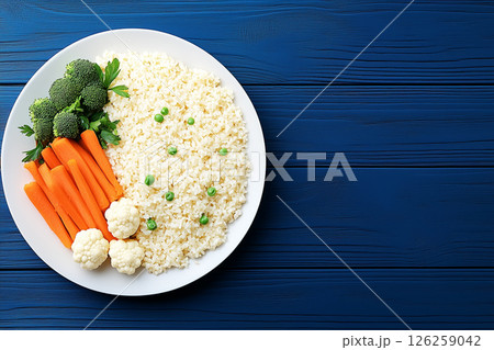 Colorful Vegan Meal Featuring Fresh Vegetables and Grains Served on a Blue Wooden Surface 126259042