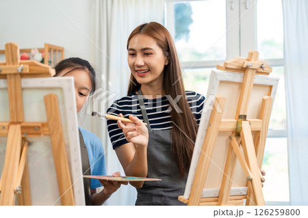 Creative bonding through art: Mother guiding daughter in painting 126259800