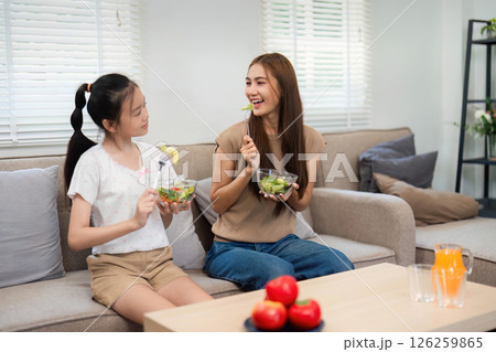Wellness in family meals: Mother and daughter enjoying healthy foods Wellness in family meals: Mother and daughter enjoying healthy foods 126259865