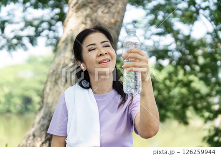 Wellness and Refreshment. Woman celebrating hydration with a water bottle after exercising outdoors. 126259944