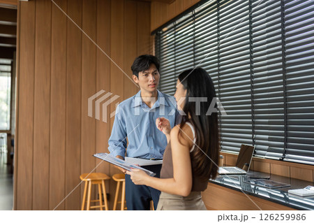 Business Discussion and Collaboration. Professionals interacting in a modern office space. 126259986