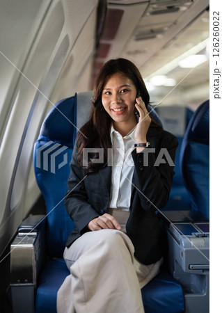 Business travel with a young woman smiling while on a call inside an airplane 126260022