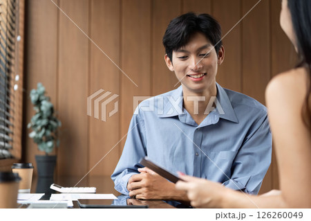 Business Meeting and Collaboration. Young professionals discussing financial reports in a modern office. 126260049