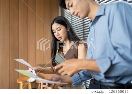 Business Interaction and Document Review. Professionals discussing project details in a stylish office setting. Business Interaction and Document Review. Professionals discussing project details in a stylish office setting. 126260055
