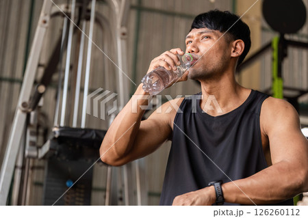 Fitness Hydration. Man drinking water during a gym workout to stay refreshed. Fitness Hydration. Man drinking water during a gym workout to stay refreshed. 126260112