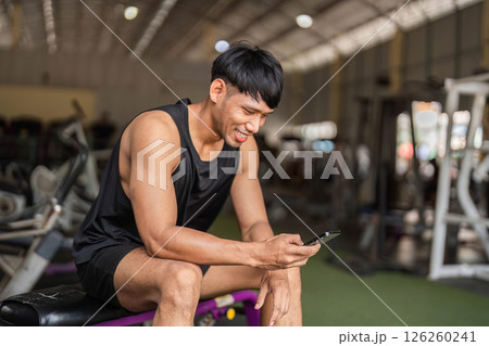 Fitness Enthusiast Checking Progress on Smartphone in Gym 126260241