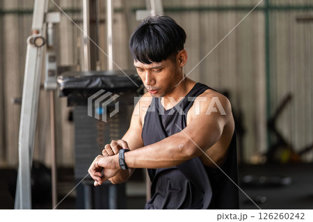 Fitness Tracking. Athlete checking smartwatch during workout in gym. Fitness Tracking. Athlete checking smartwatch during workout in gym. 126260242