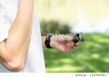 Wellness and Mindfulness. Close-up of a senior man's hand holding headphones, symbolizing relaxation. Wellness and Mindfulness. Close-up of a senior man's hand holding headphones, symbolizing relaxation. 126260263