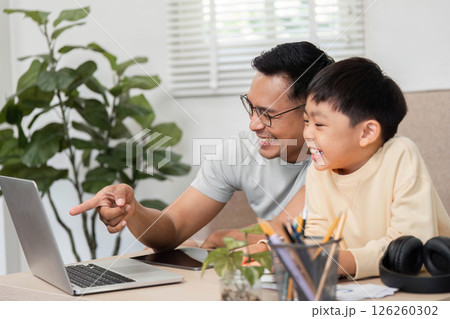 Homeschool fun between father and son exploring a laptop Homeschool fun between father and son exploring a laptop 126260302