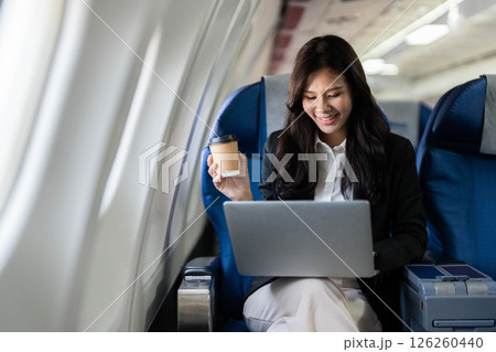 Business travel: Professional woman working on laptop in airplane 126260440