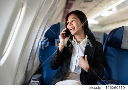 Business travel with woman smiling while talking on a phone in an airplane 126260510