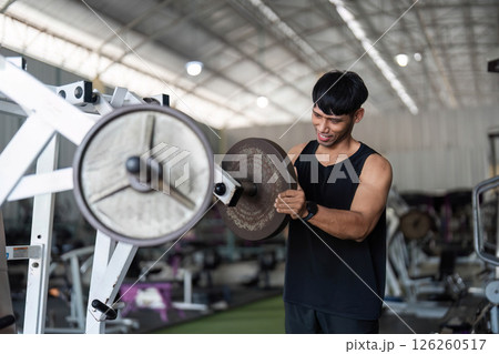Fitness Focus. Young man engaging in weightlifting for strength enhancement in gym. 126260517