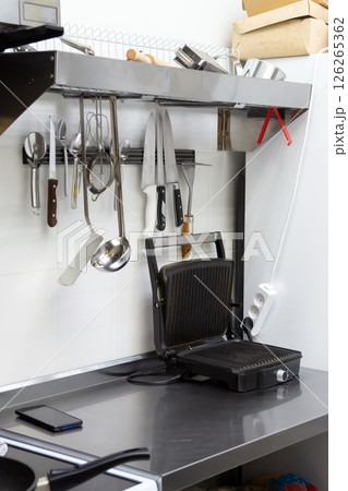 Professional Kitchen Tools Hang Above Black Countertop Professional Kitchen Tools Hang Above Black Countertop 126265362