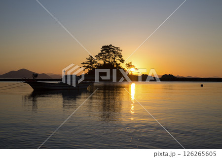 The sun rises on the horizon beyond the small island The sun rises on the horizon beyond the small island 126265605