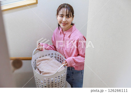 洗濯かごを持つ若い女性 126266111