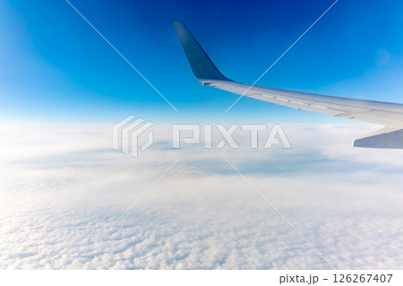 View from the airplane window at a beautiful cloudy sky and the airplane wing View from the airplane window at a beautiful cloudy sky and the airplane wing 126267407