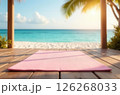 Pink yoga mat lying on wooden terrace, clear seascape blurred in background 126268033