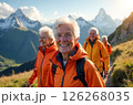 Company of happy elderly people in orange jackets on a walk along mountain trails 126268035