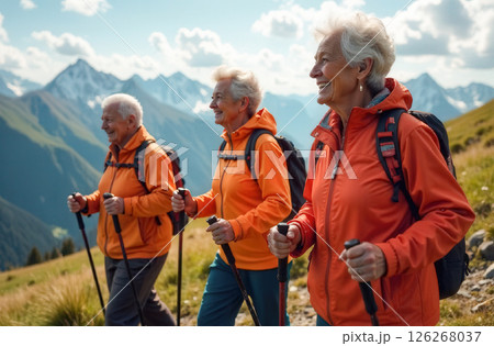 Elderly women in orange jackets hiking with trekking poles in the mountains Elderly women in orange jackets hiking with trekking poles in the mountains 126268037