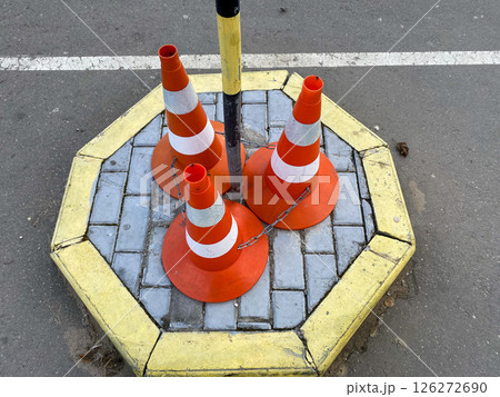 Orange traffic cones are chained together on an asphalt roadway Orange traffic cones are chained together on an asphalt roadway 126272690