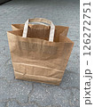 A paper shopping bag stands on the pavement in the street, vertical picture 126272751