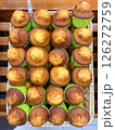 Freshly made cupcakes are laid out in a row on the counter in the store, vertical picture 126272759