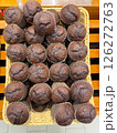 Freshly baked chocolate cupcakes are lined up in a row on the counter at the store, vertical picture 126272763