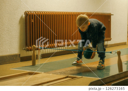 oung boy playing indoor bowling, concentrating intently as he carefully releases the ball towards the pins. Casual setting with a focus on the playful moment. 126273165