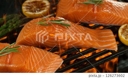 Close-up of Delicious Salmon Fillets on a Grill with Roaring Flames 126273602