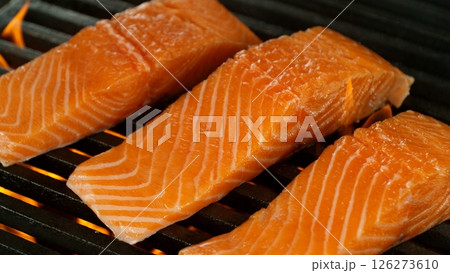 Close-up of Delicious Salmon Fillets on a Grill with Roaring Flames Close-up of Delicious Salmon Fillets on a Grill with Roaring Flames 126273610