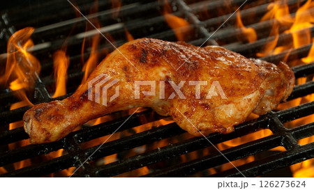 Close-up of Delicious Chicken Legs on a Grill with Roaring Flames 126273624