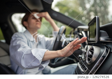 Woman drives car with broken air conditioner in hot weather wipes sweat on face. Woman drives car with broken air conditioner in hot weather wipes sweat on face. 126274526