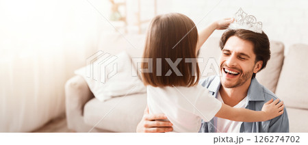 Little girl putting crown on her laughing dad head, having fun together at home, close up 126274702