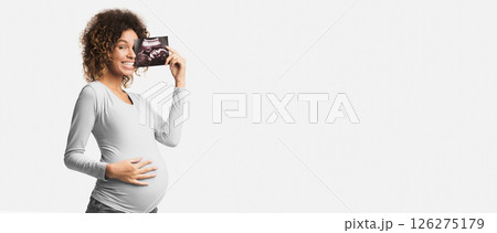 Happy pregnant woman enjoying photo of her unborn child, anticipating her future life, white background Happy pregnant woman enjoying photo of her unborn child, anticipating her future life, white background 126275179