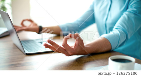 Unrecognizable Arab guy meditating in front of laptop pc, making gyan mudra with both hands, trying to keep calm at workplace, closeup. Stress management, work life balance concept Unrecognizable Arab guy meditating in front of laptop pc, making gyan mudra with both hands, trying to keep calm at workplace, closeup. Stress management, work life balance concept 126275180