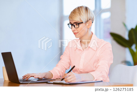 Female Entrepreneurship. Confident Businesswoman Working On Laptop Taking Notes Sitting In Modern Office. Selective Focus Female Entrepreneurship. Confident Businesswoman Working On Laptop Taking Notes Sitting In Modern Office. Selective Focus 126275185