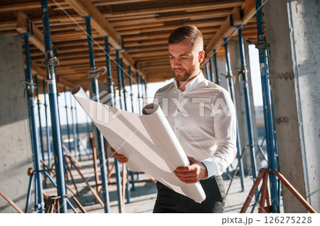 Standing and reading plan. Man is working on the construction site at daytime Standing and reading plan. Man is working on the construction site at daytime 126275228