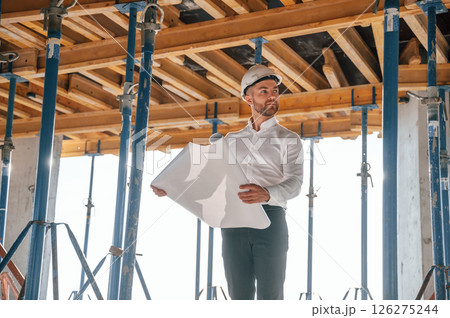 Beautiful sunlight. Walking with plan in hands. Man is working on the construction site at daytime 126275244