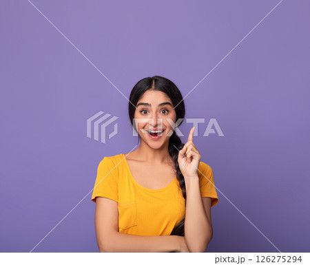 Inspiration, Creativity, Solution, Eureka concept. Portrait of excited young indian woman in yellow t-shirt raising finger up and smiling, having wow creative idea, purple studio background, copyspace 126275294