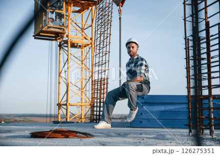 Sitting and taking a break. Man is working on the construction site at daytime Sitting and taking a break. Man is working on the construction site at daytime 126275351