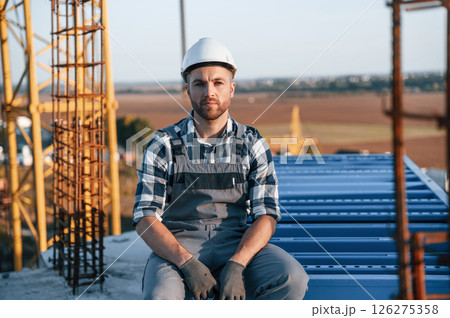 Sitting and taking a break. Man is working on the construction site at daytime Sitting and taking a break. Man is working on the construction site at daytime 126275358
