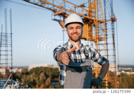 Standing and smiling. Man is working on the construction site at daytime 126275390