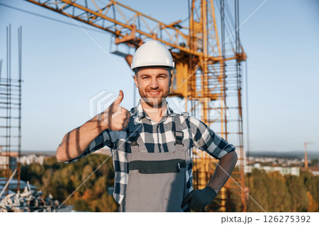 Standing and smiling. Man is working on the construction site at daytime Standing and smiling. Man is working on the construction site at daytime 126275392