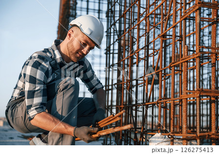 Working with metal material. Man is on the construction site at daytime Working with metal material. Man is on the construction site at daytime 126275413